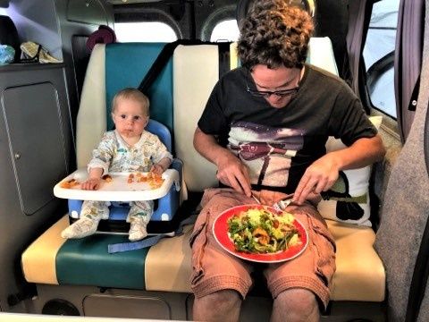 Alasdair and his baby eating inside campervan