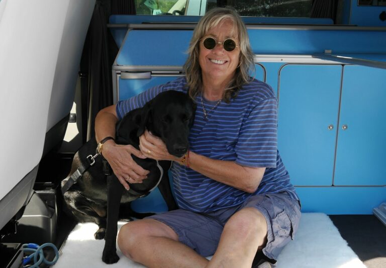 Campervan owner sitting with her black dog
