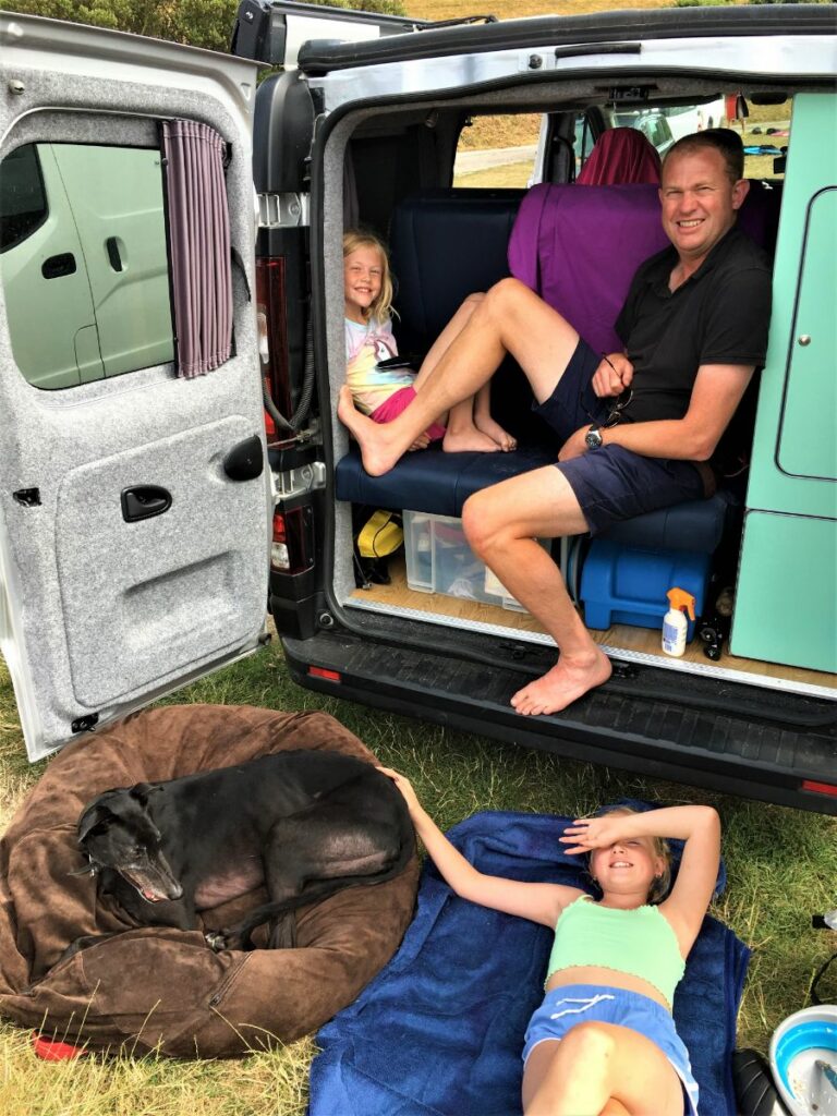 family at the back of their campervan with their dog